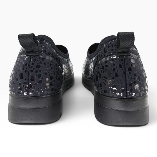 The Shoe Shop Florence slip-on shoes in black with a metallic spotted pattern, featuring a pull tab and flat sole.