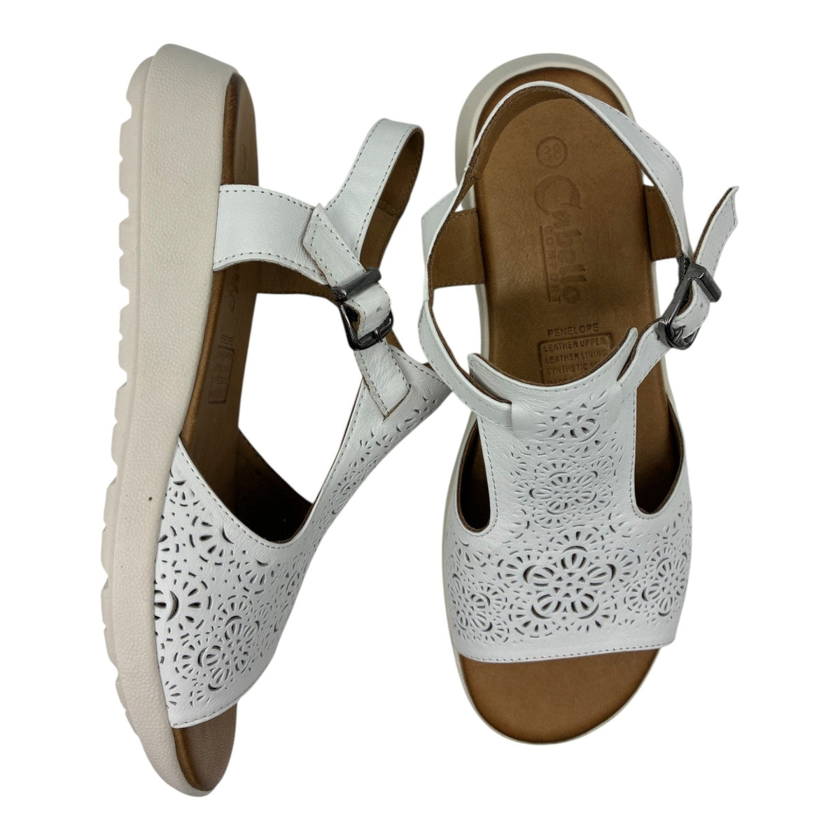 The Shoe Shop Penelope white leather sandals with laser-cut floral detailing, adjustable strap, and wedge heel.
