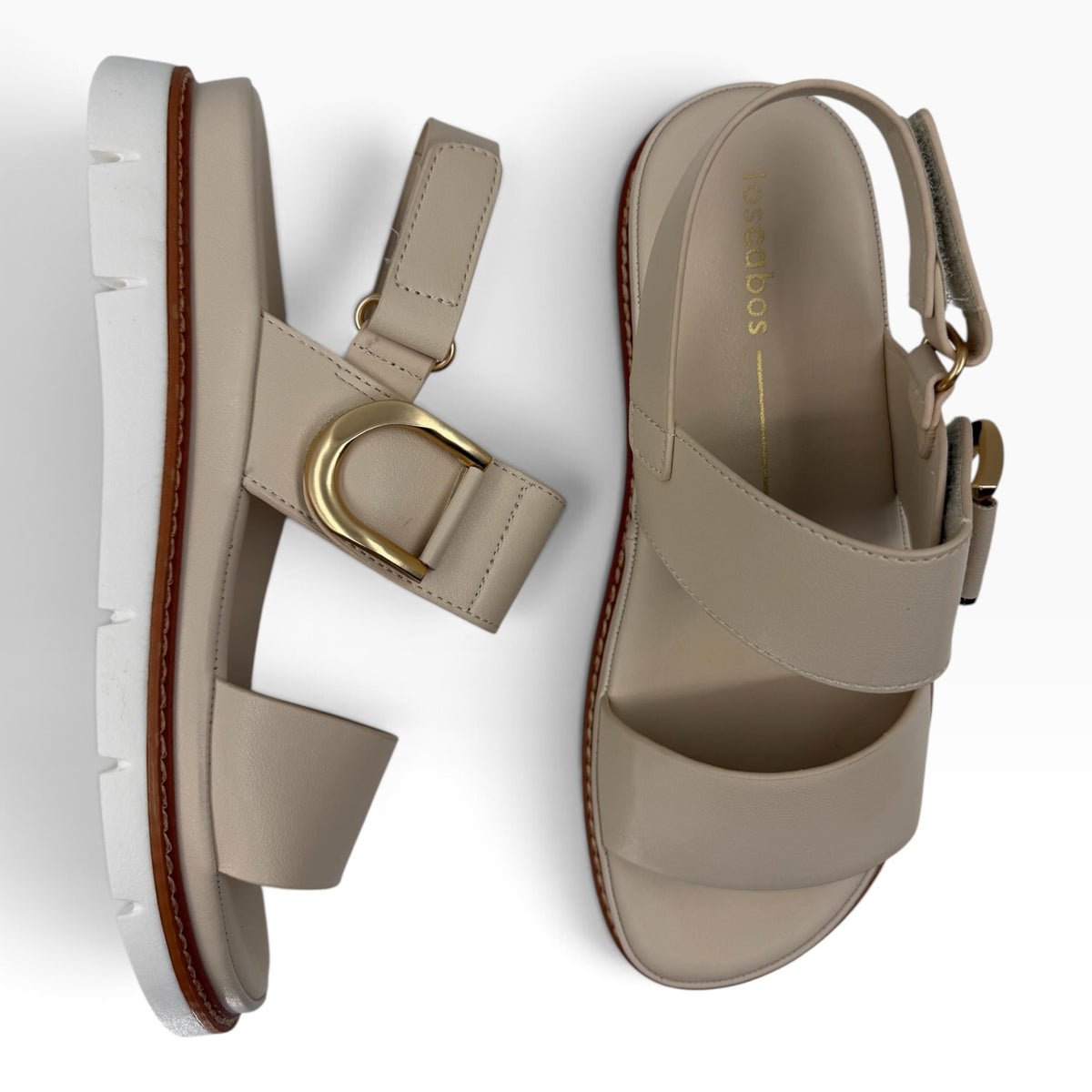 The Shoe Shop Sana beige leather wedge sandals with a gold-tone D-buckle, adjustable slingback, and lugged outsole.