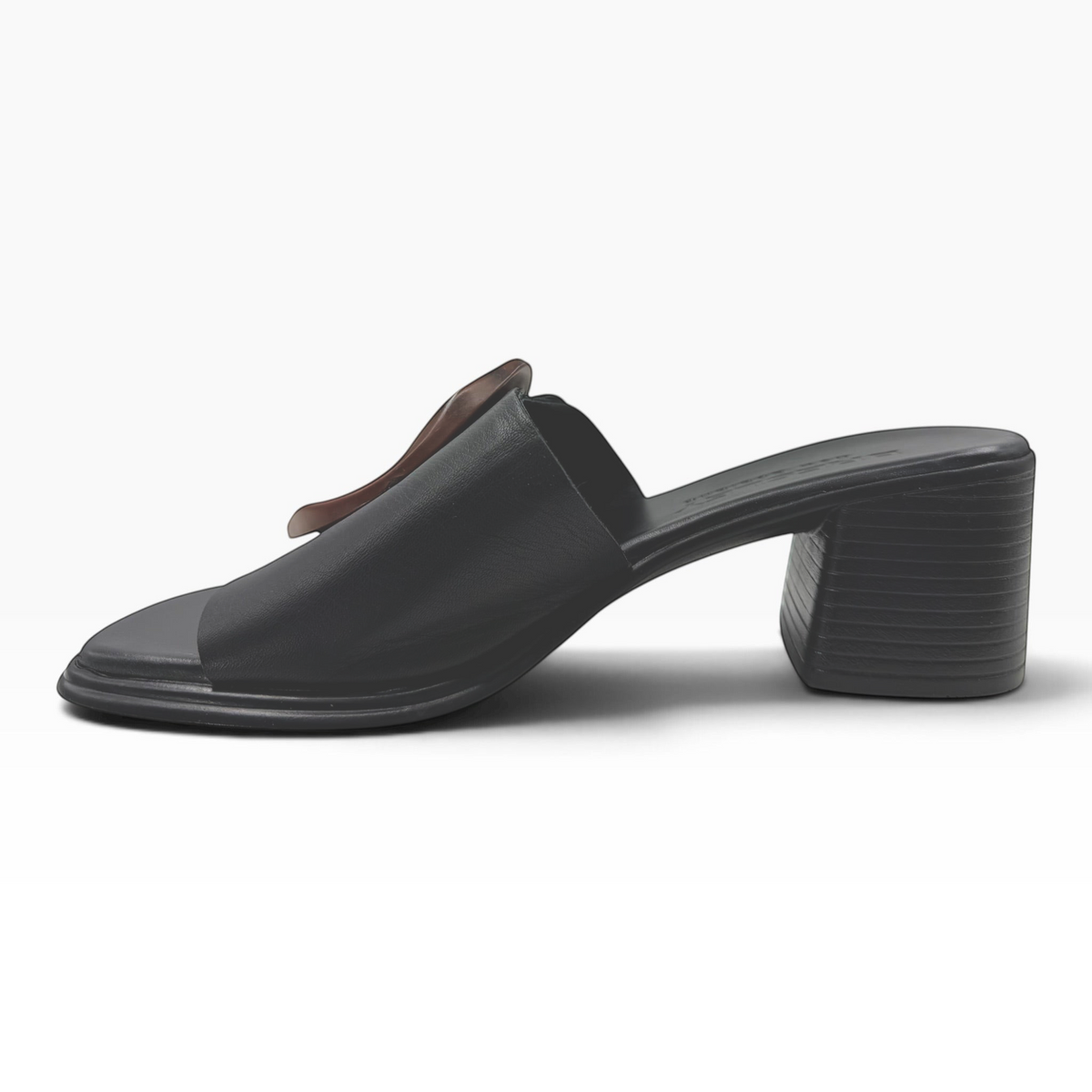The Shoe Shop Panton Slide in black leather featuring a low block heel and a tortoiseshell-effect circular ornament.