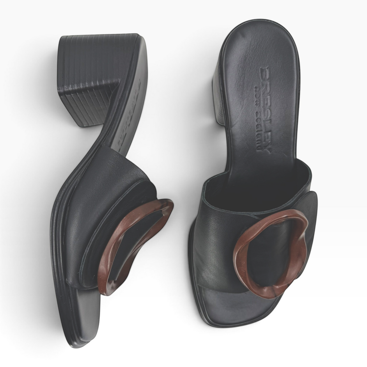 The Shoe Shop Bresley Panton black leather slides with a low block heel and tortoiseshell circular ornament.
