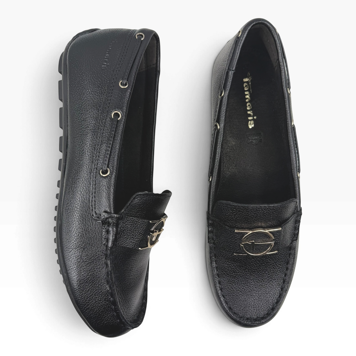 The Shoe Shop 24630 black leather loafers with gold-tone hardware and flexible rubber driving soles, top view.