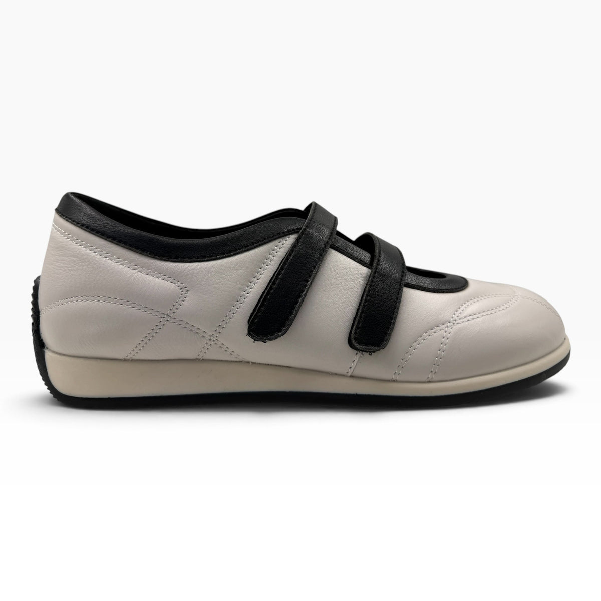 The Shoe Shop Amor flat in white and black leather with twin adjustable hook-and-loop straps and a rubber sole.
