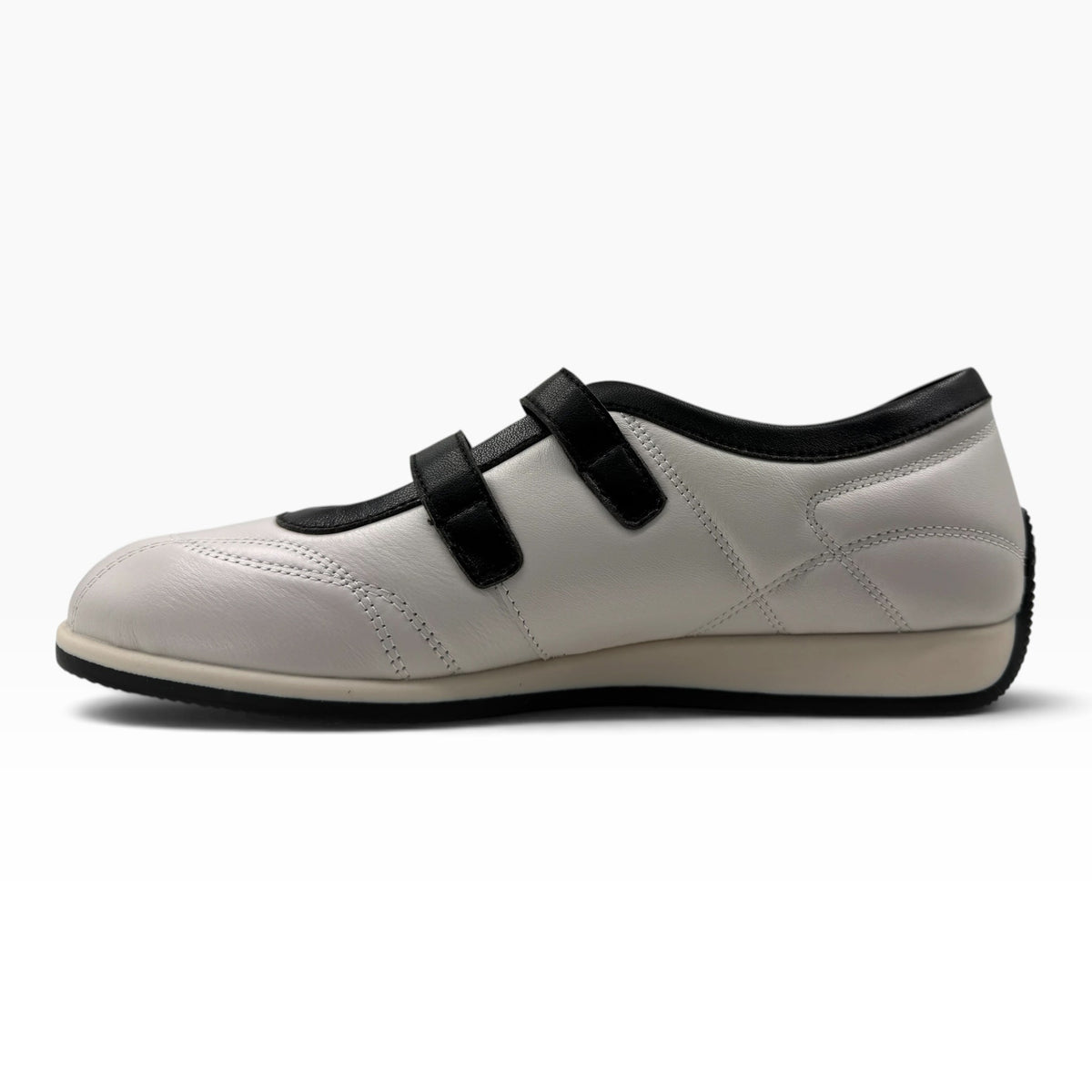 The Shoe Shop Amor flat in white leather with black adjustable hook-and-loop straps and a lightweight rubber sole.