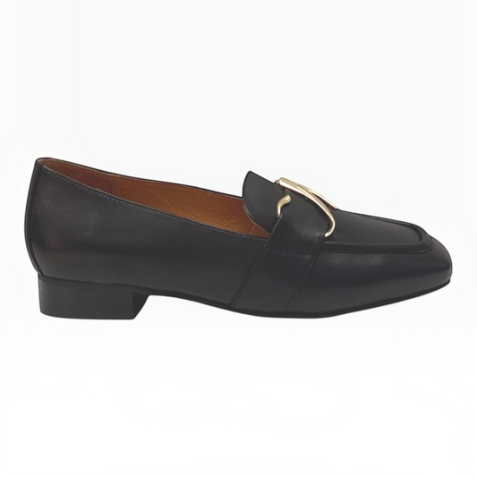 The Shoe Shop Sinamon black leather loafer with a gold-tone buckle, stitched apron front, and low stacked heel.