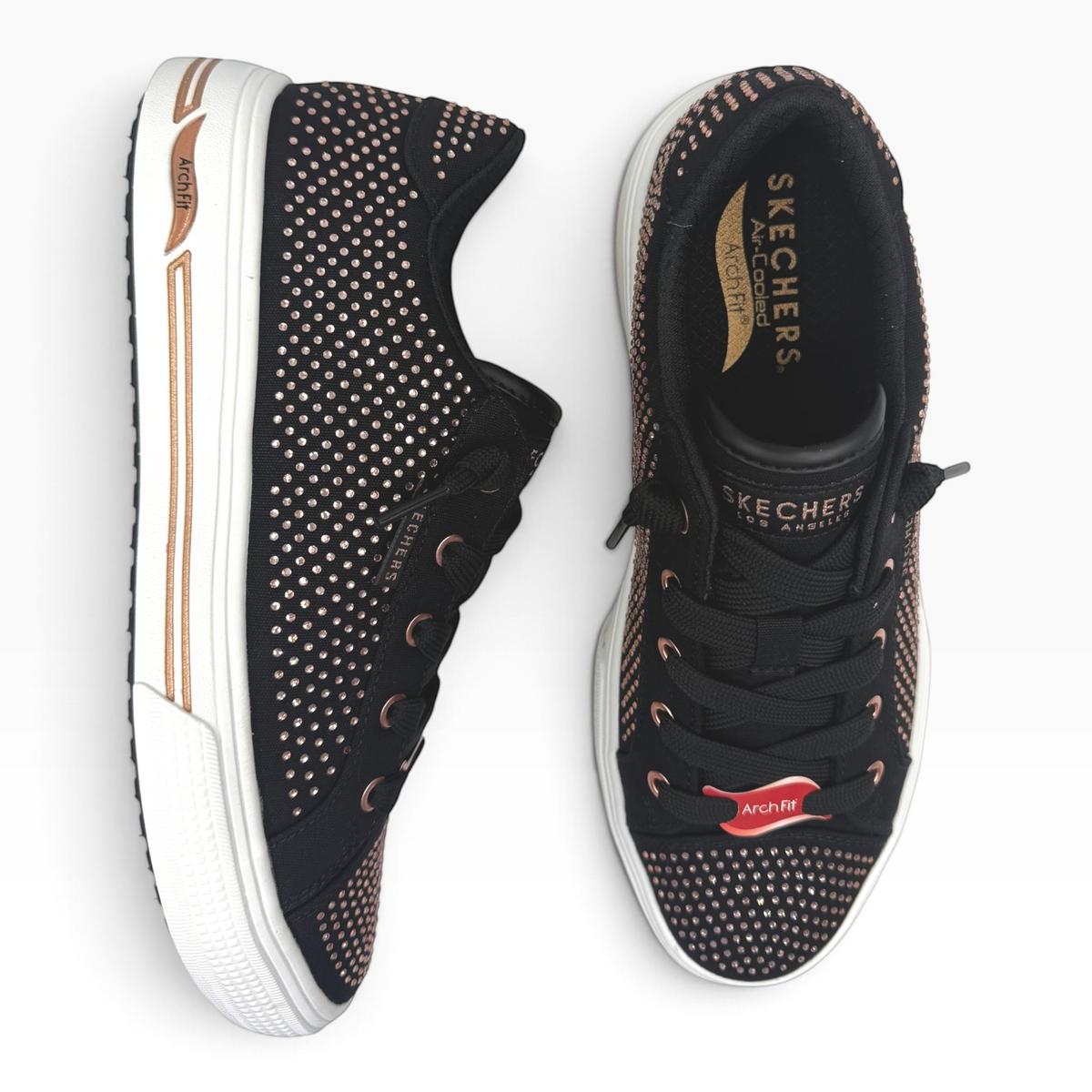 The Shoe Shop Skechers Arch Fit Arcade Gem Steps black canvas sneakers with rose gold metallic stud embellishments.