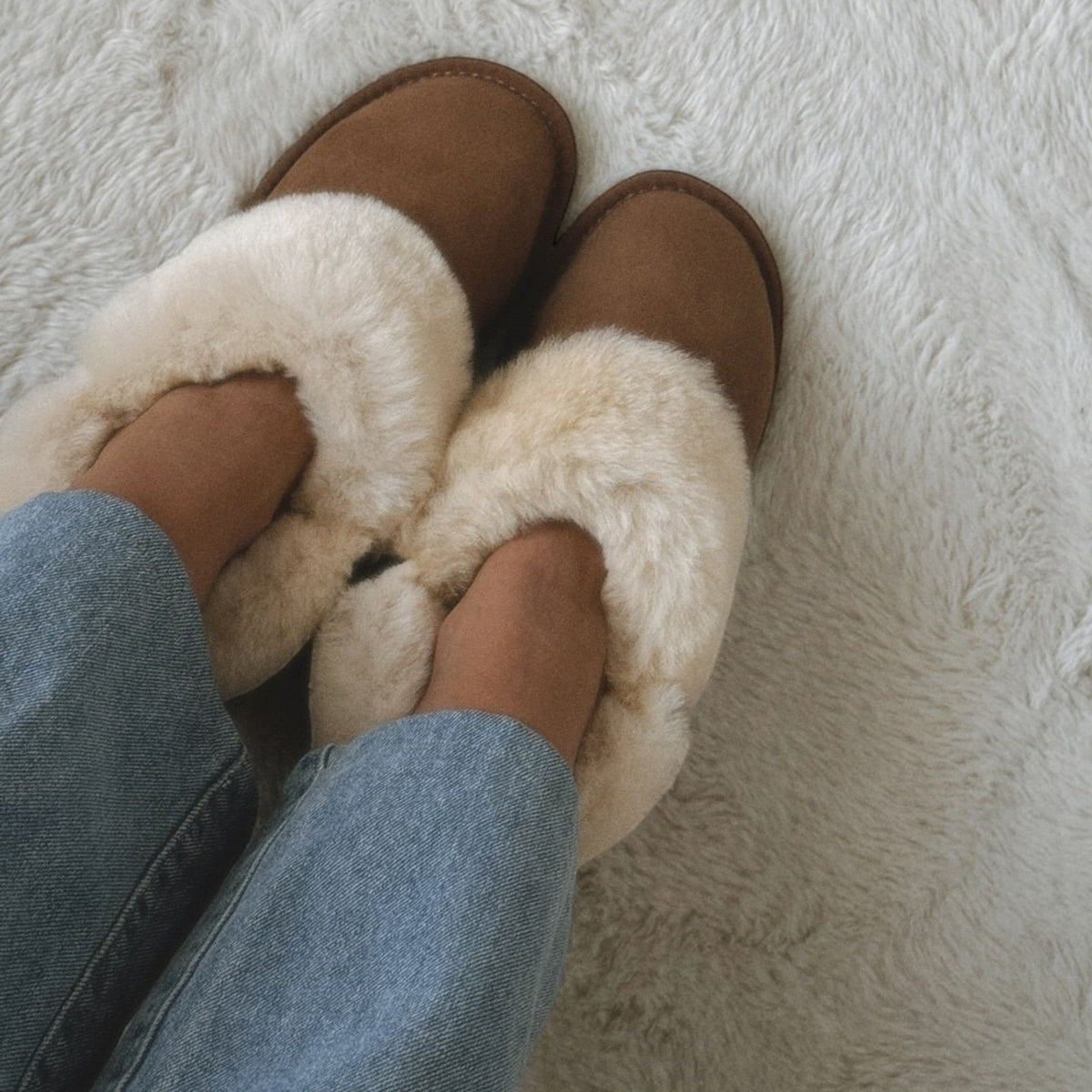 The Shoe Shop EMU Platinum Mintaro slippers in brown sheepskin with plush cream lining worn with blue jeans.