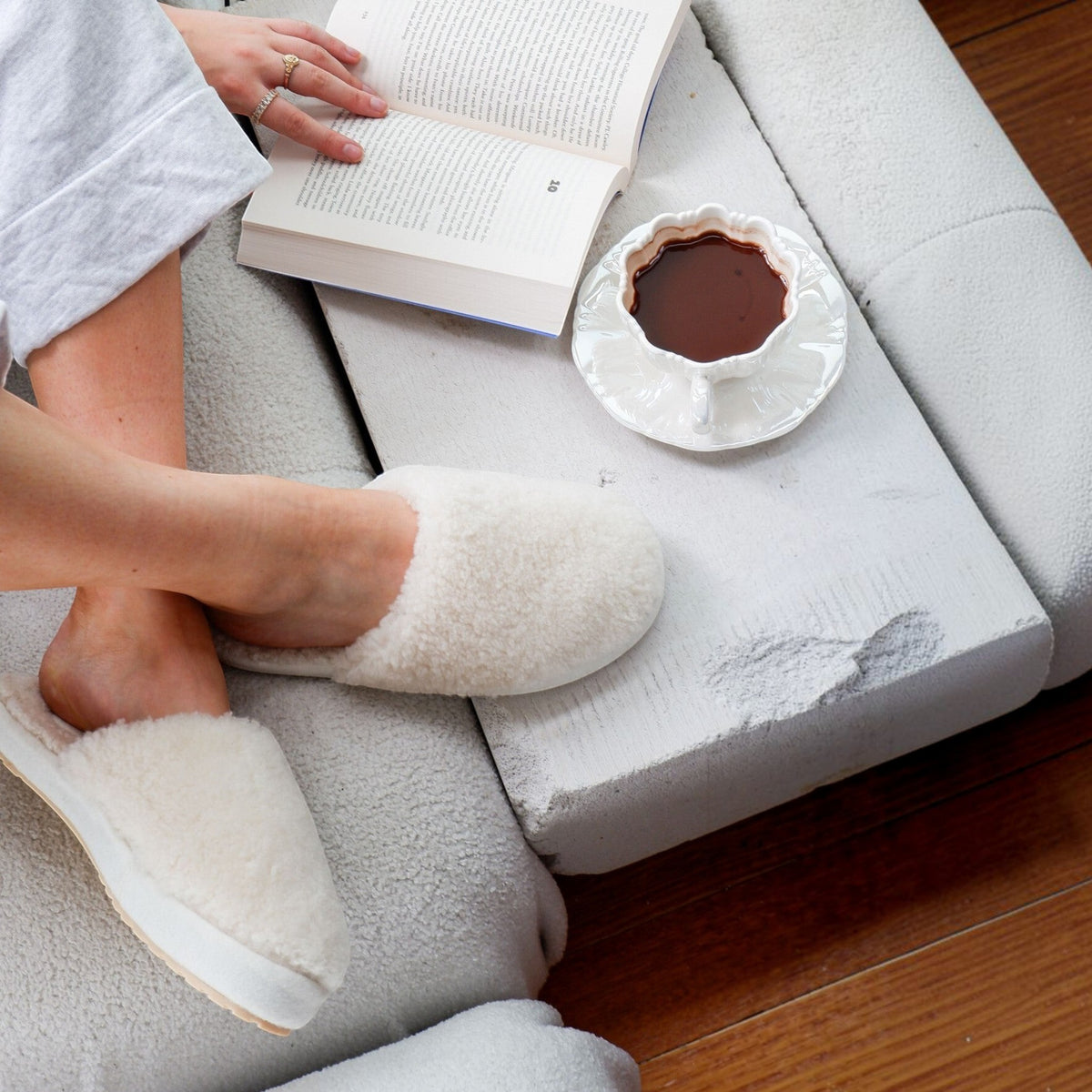 The Shoe Shop EMU Starley cream sheepskin slippers with plush wool texture worn while reading on a cozy sofa