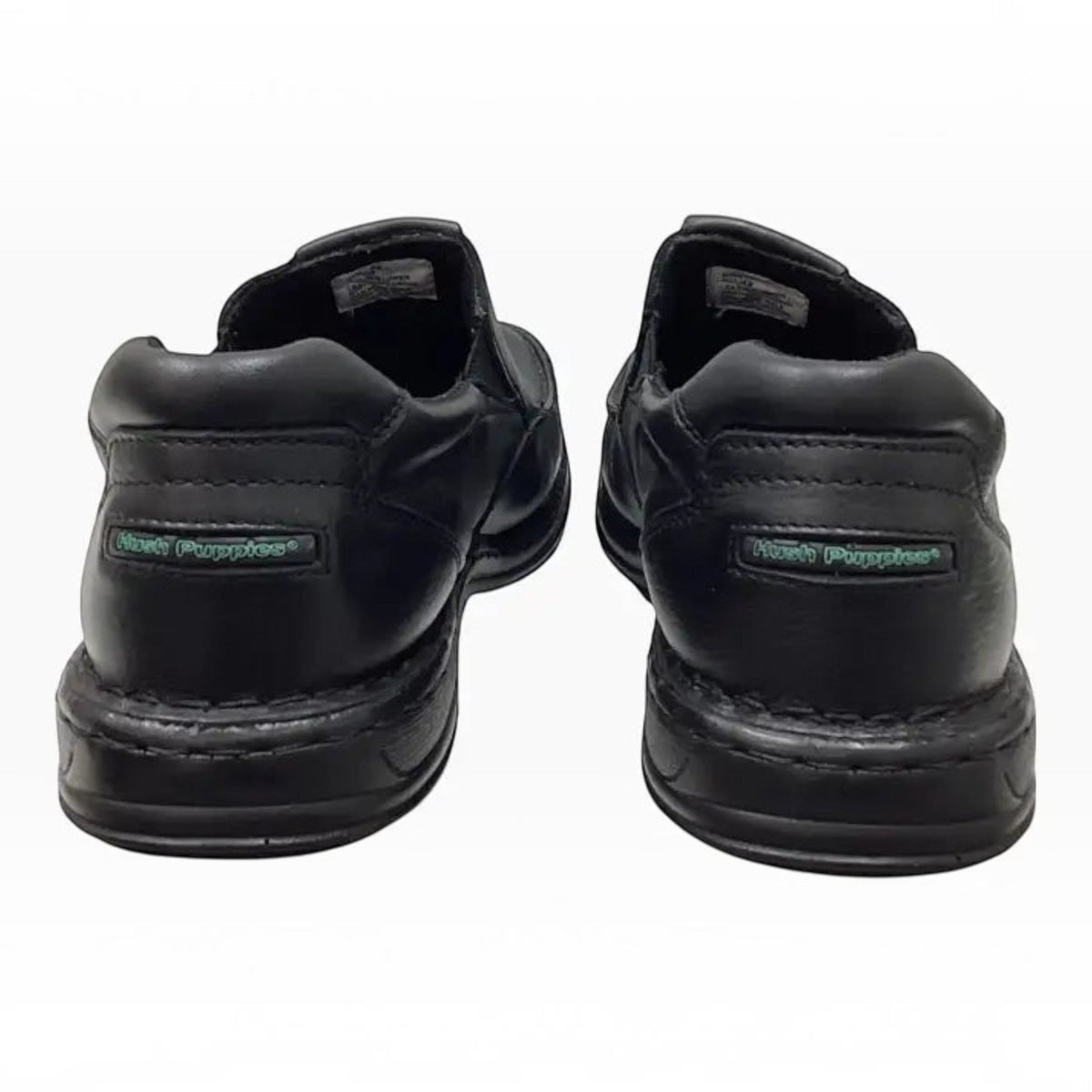 The Shoe Shop Hush Puppies Sawyer II black leather boat-style walkers showing the heel view with branded detailing.
