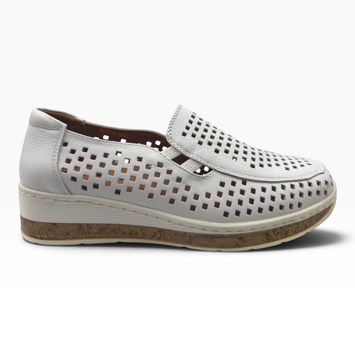 The Shoe Shop Monkey casual slip-on shoe in white leather with a laser-cut square pattern and cork-effect wedge sole.