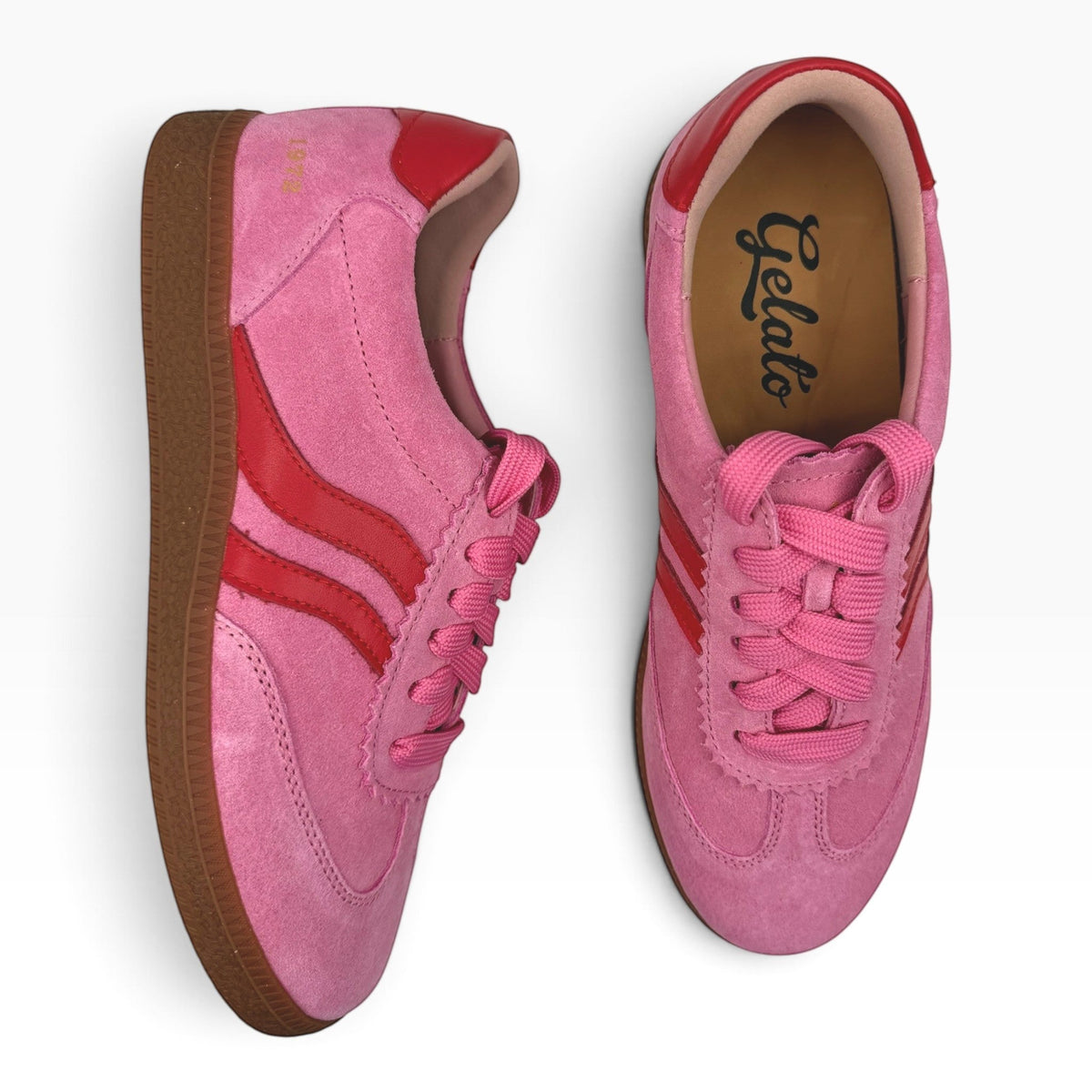 The Shoe Shop Hamptons pink suede sneakers with red leather accents and a gum rubber sole, top-down view.