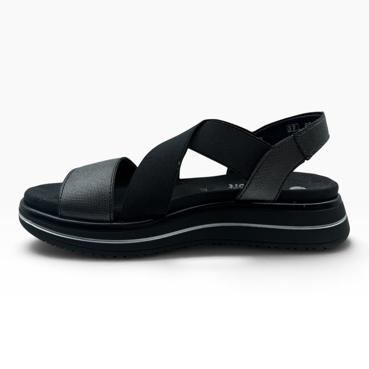 The Shoe Shop Sabrina sandal in black with elastic cross-straps, metallic front detail, and a cushioned flatform sole