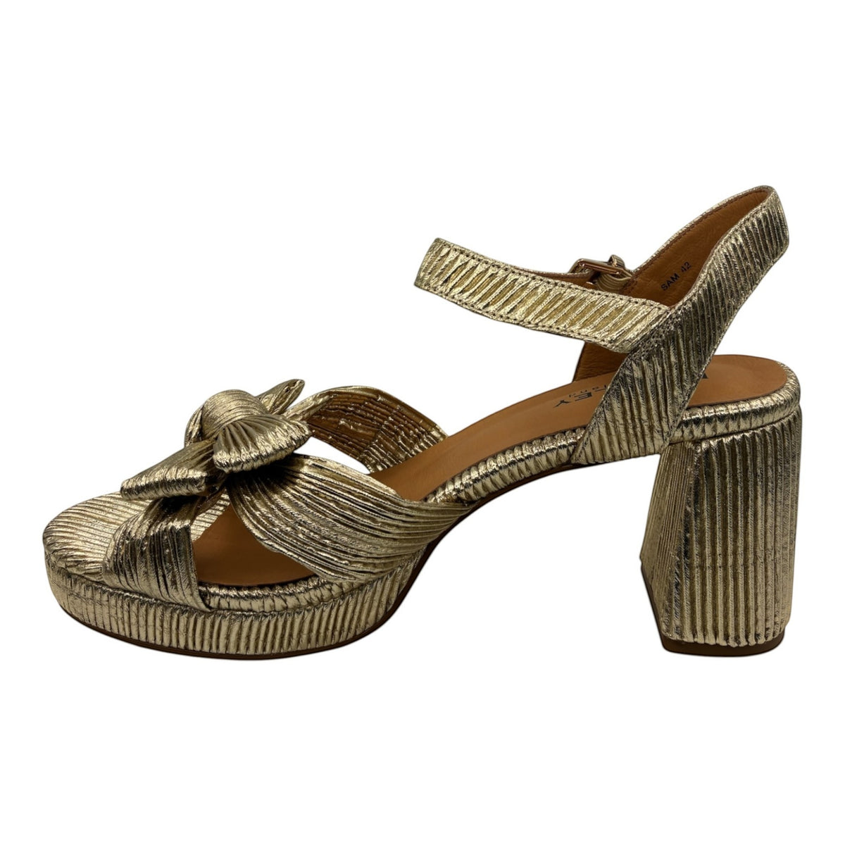 The Shoe Shop Sam gold metallic platform heel with a knotted bow, adjustable ankle strap, and chunky block heel.