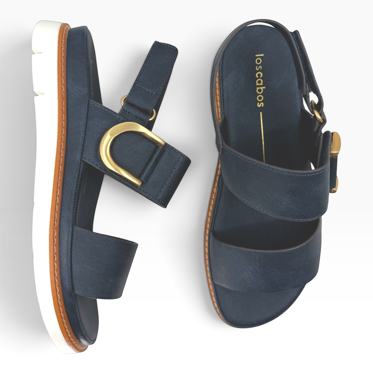 The Shoe Shop Sana wedge sandal in navy leather with a gold-tone buckle, slingback strap, and white lugged outsole.