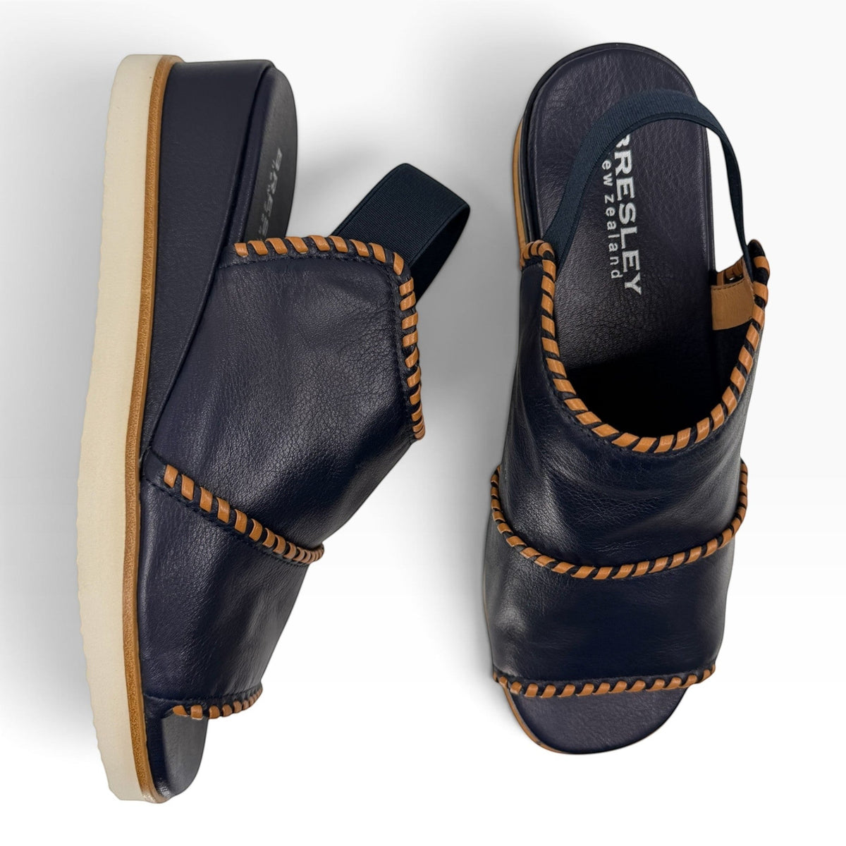 The Shoe Shop Sigma navy leather wedge sandals featuring contrast tan whipstitching and an elasticated slingback strap.
