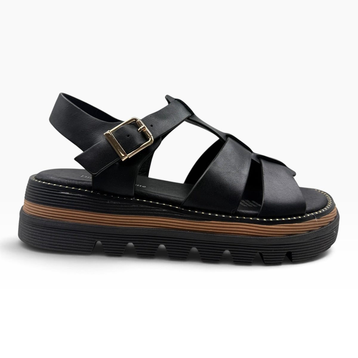 The Shoe Shop Sylvera black leather platform sandal with wide cross-straps, gold buckle, and ridged rubber sole.