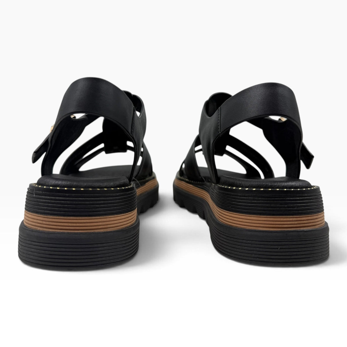 The Shoe Shop Sylvera black leather platform sandals with chunky ridged rubber soles and tan welt detail, back view.