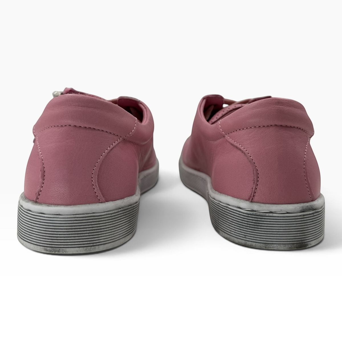 Rear view of The Shoe Shop Tommie Perf pink leather sneakers with textured rubber soles on a white background