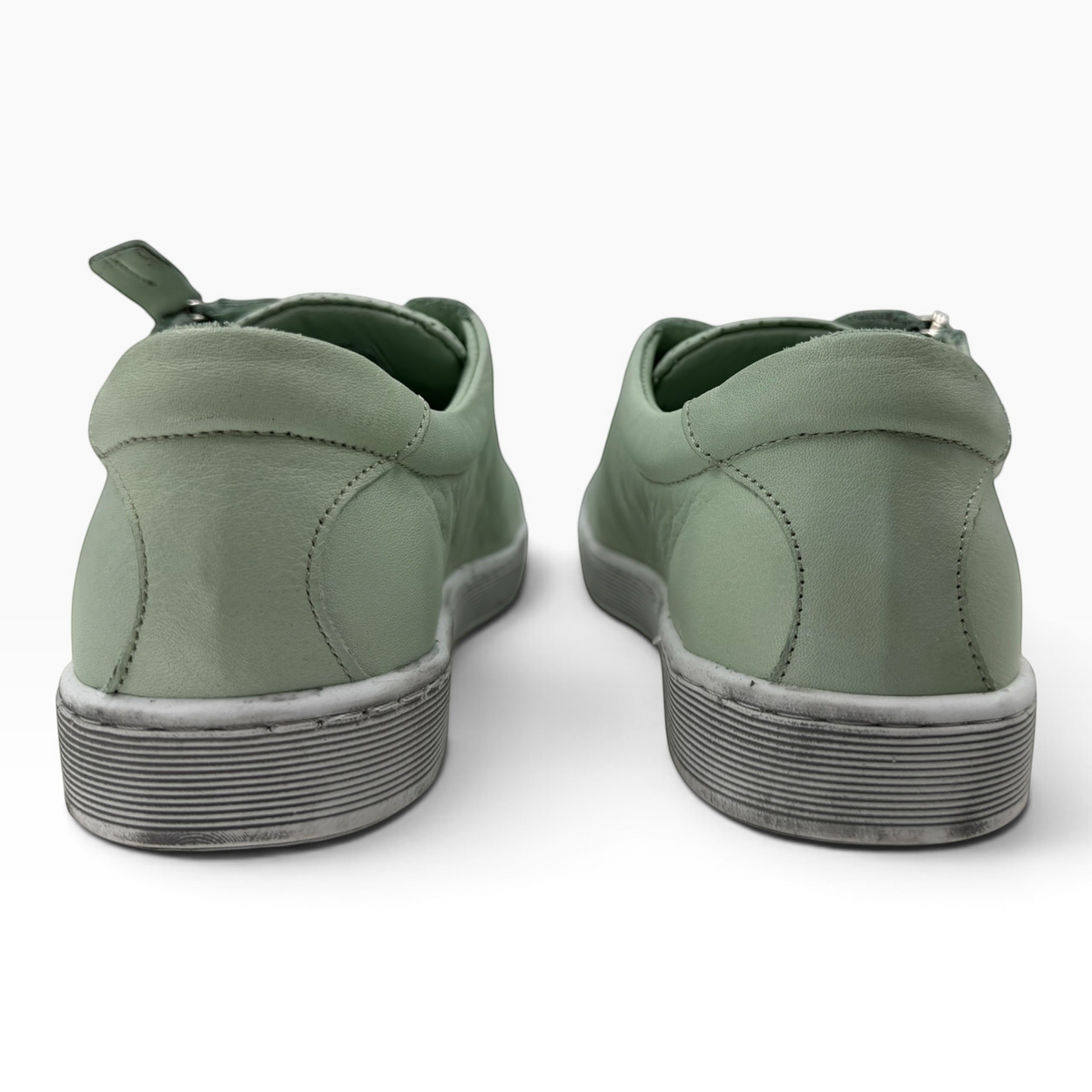 The Shoe Shop Tommie Perf sage green leather sneakers viewed from the back showing rubber soles and side zip detail.