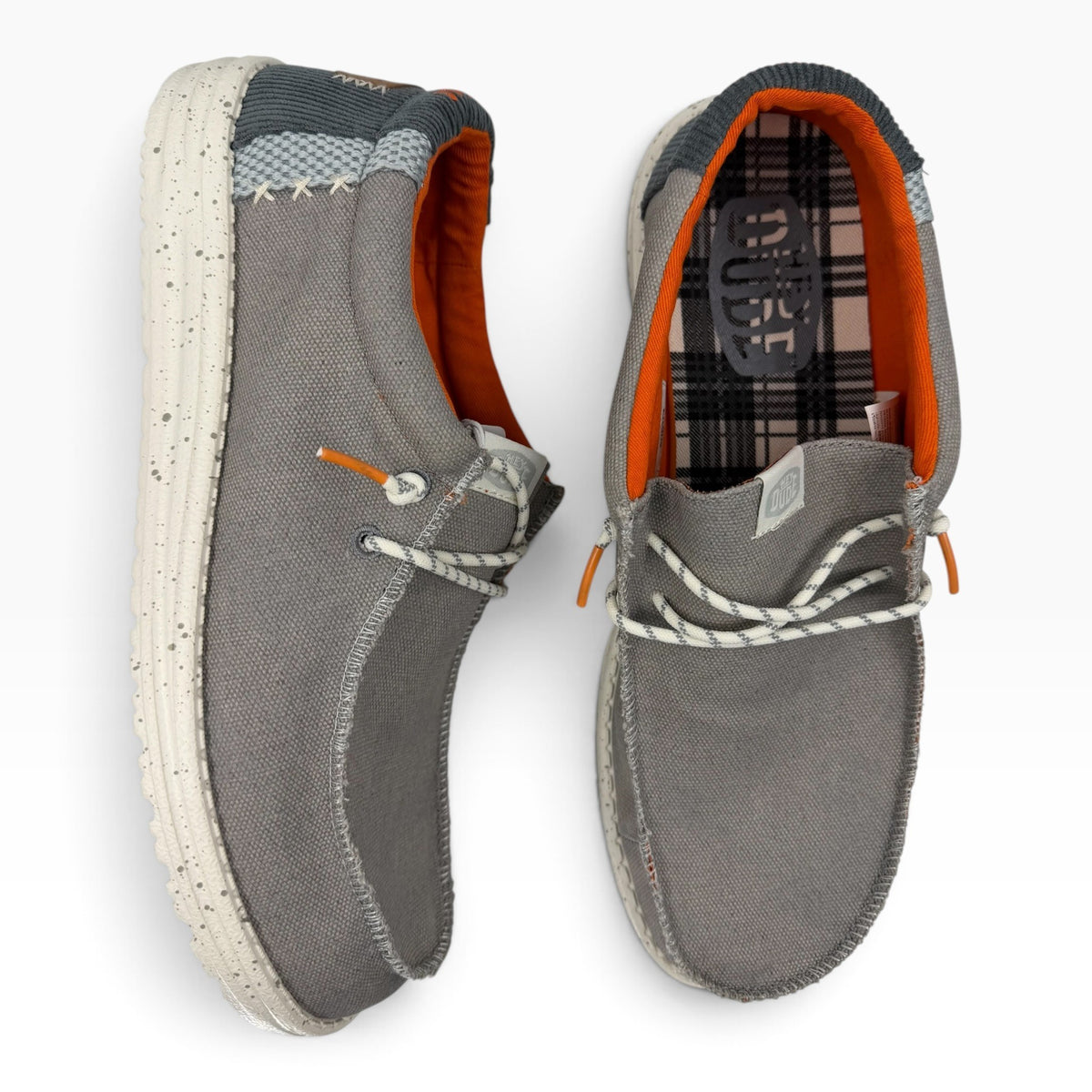 The Shoe Shop Wally grey canvas slip-on shoes with orange lining, speckled white soles, and plaid interior detail.