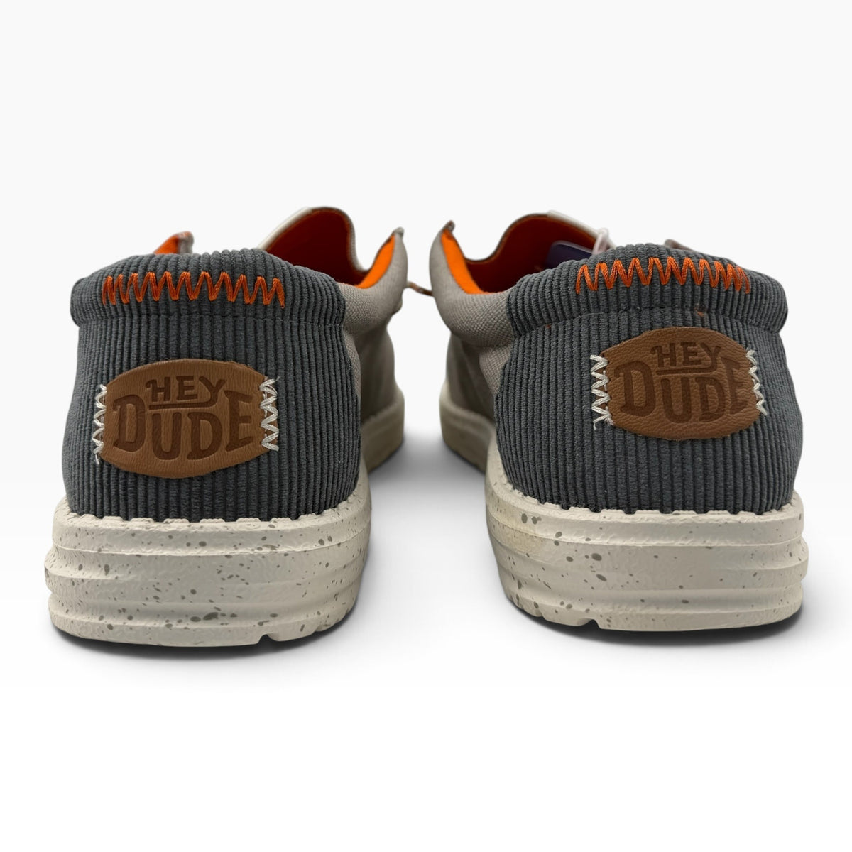 The Shoe Shop Wally grey corduroy slip-on shoes with orange stitching and speckled white soles, rear view.